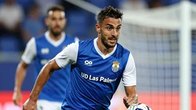 A photorealistic image of a UD Las Palmas player, wearing a blue jersey with white sleeves and a white collar, in a tight...