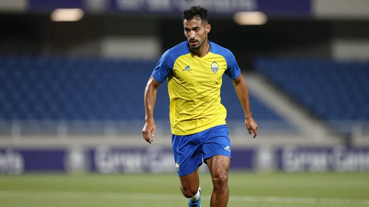 A muscular UD Las Palmas midfielder, late 20s, in a plain yellow and blue training top, sprints with the ball at his...